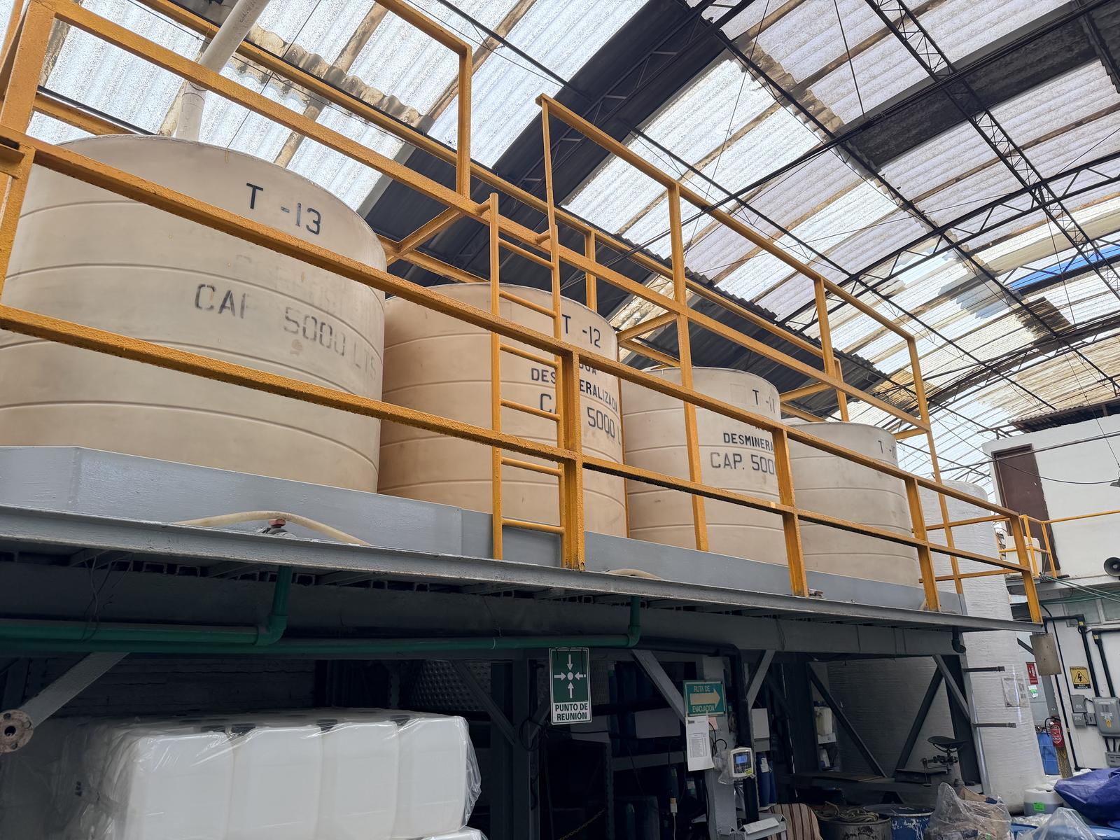 Tanques de almacenamiento de agua desmineralizada de 5,000 litros en planta Akim de México, estructura elevada con barandal de seguridad industrial